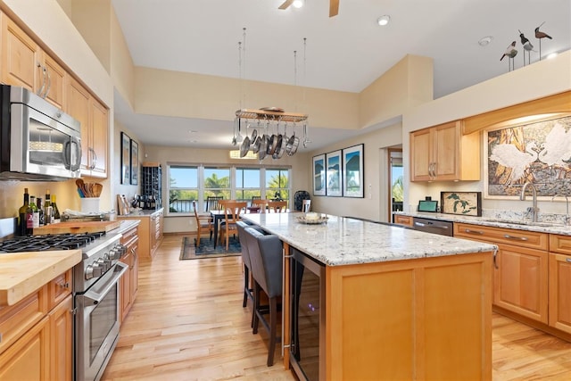 kitchen with a center island, sink, wine cooler, light wood-type flooring, and stainless steel appliances