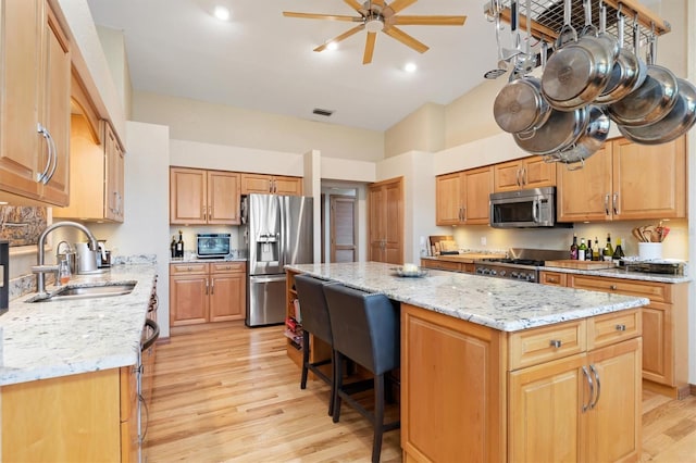 kitchen featuring ceiling fan, sink, stainless steel appliances, light hardwood / wood-style flooring, and a kitchen island