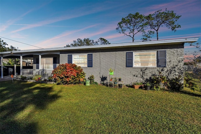 view of front of home featuring brick siding, a porch, and a lawn