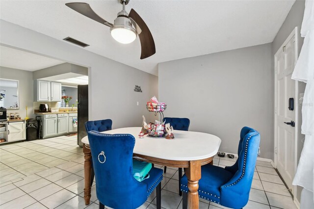 tiled dining room featuring ceiling fan and sink