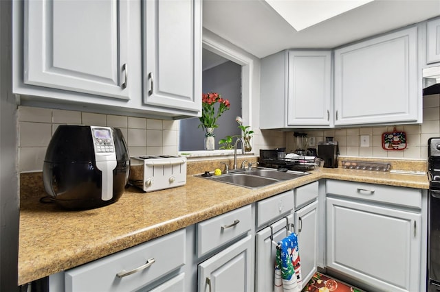 kitchen featuring white cabinets, decorative backsplash, and sink