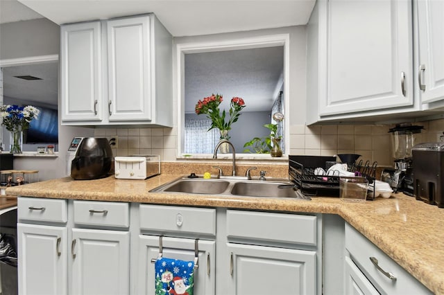 kitchen featuring backsplash, white cabinetry, and sink