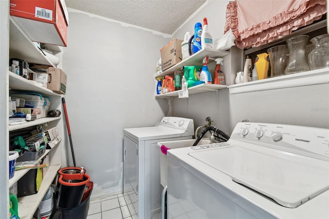 clothes washing area with washer and clothes dryer, light tile patterned floors, and a textured ceiling