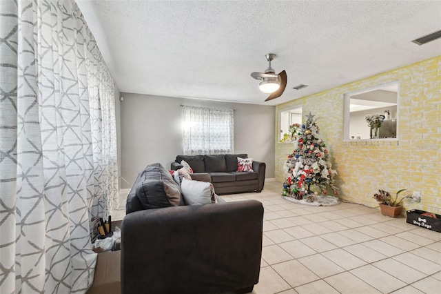 living room featuring ceiling fan, light tile patterned floors, and a textured ceiling