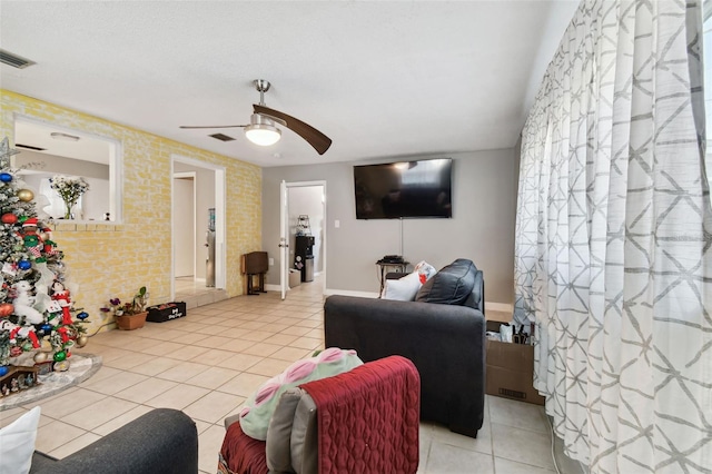 tiled living room featuring ceiling fan and brick wall