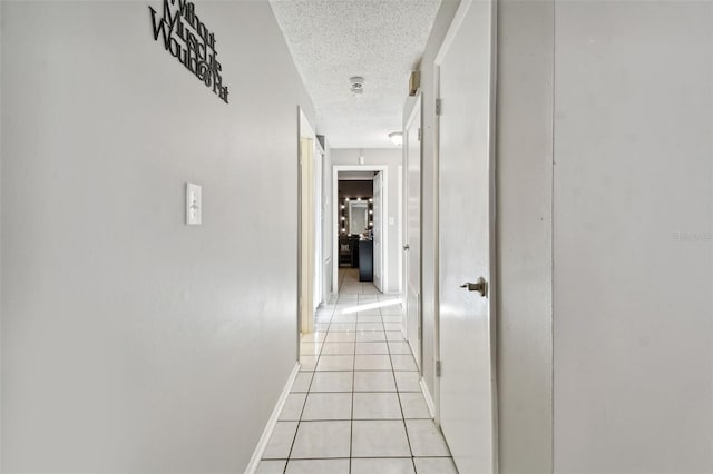 hall featuring a textured ceiling and light tile patterned flooring