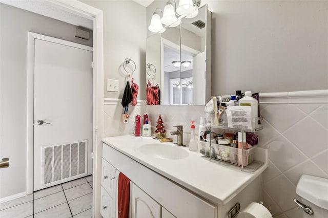 bathroom with tile patterned flooring, vanity, toilet, and tile walls