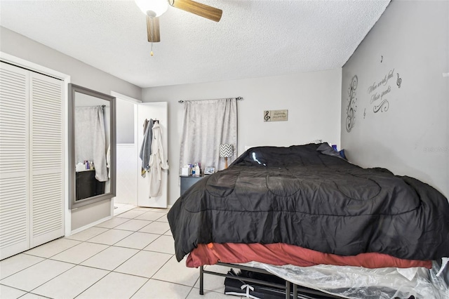 bedroom featuring a textured ceiling, a closet, ceiling fan, and light tile patterned flooring