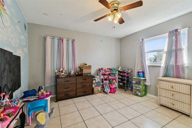 playroom with ceiling fan, light tile patterned flooring, and a textured ceiling