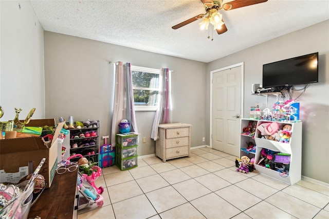 game room featuring a textured ceiling, ceiling fan, and light tile patterned flooring