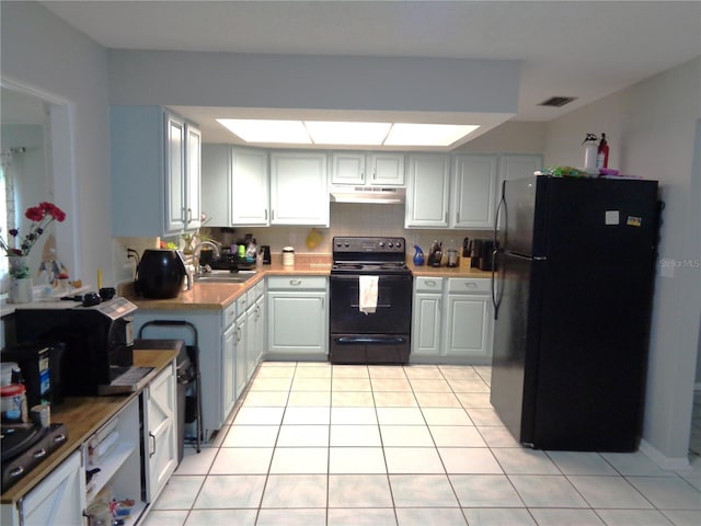 kitchen with tasteful backsplash, visible vents, light tile patterned floors, under cabinet range hood, and black appliances