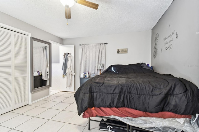bedroom featuring a textured ceiling, a closet, light tile patterned floors, and a ceiling fan