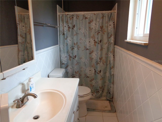 full bath featuring toilet, tile patterned floors, a wainscoted wall, and vanity