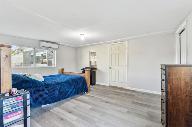 bedroom with a wall mounted AC, wood finished floors, and baseboards