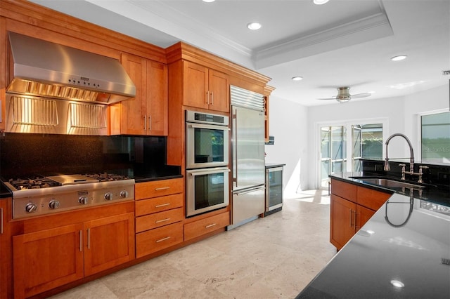 kitchen with ceiling fan, sink, stainless steel appliances, wall chimney range hood, and wine cooler