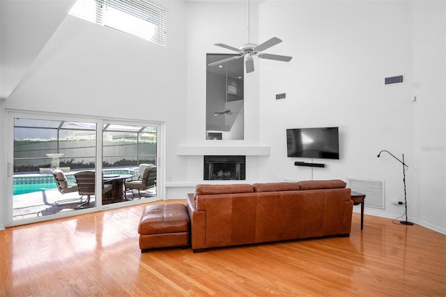 living room featuring ceiling fan, hardwood / wood-style floors, and a towering ceiling