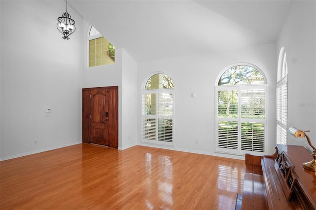 entryway featuring hardwood / wood-style floors, an inviting chandelier, and high vaulted ceiling