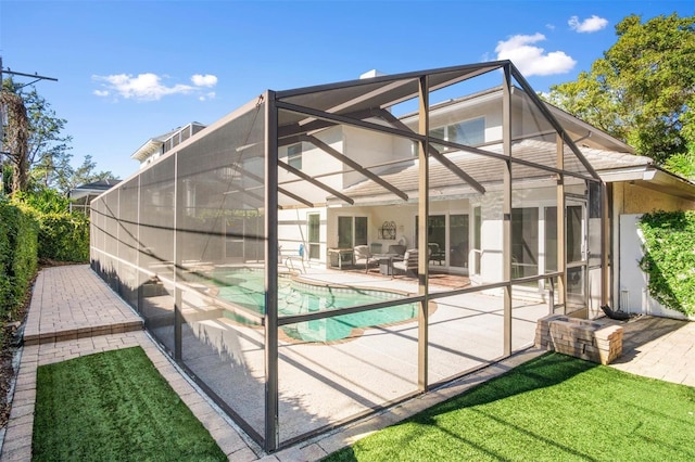 rear view of house featuring a patio area, a yard, and glass enclosure