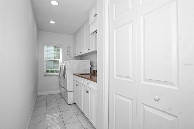 clothes washing area featuring sink, cabinets, and independent washer and dryer