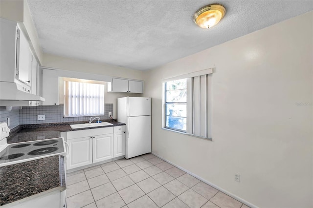 kitchen featuring white cabinets, plenty of natural light, white fridge, and sink