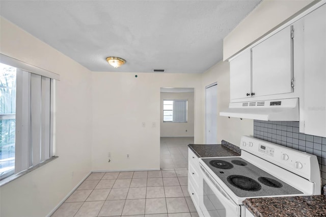 kitchen with light tile patterned floors, electric range, tasteful backsplash, and white cabinetry