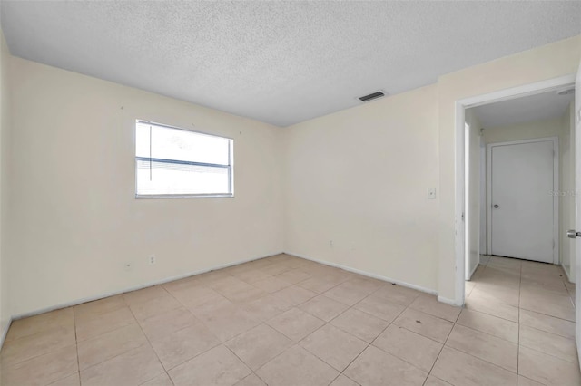 tiled spare room with a textured ceiling