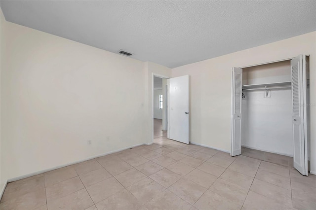 unfurnished bedroom with light tile patterned floors, a textured ceiling, and a closet