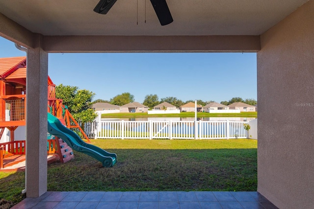 view of yard featuring a playground, ceiling fan, and a water view