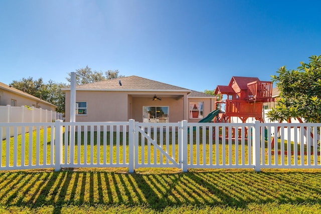 view of front of home featuring a playground, ceiling fan, and a front lawn