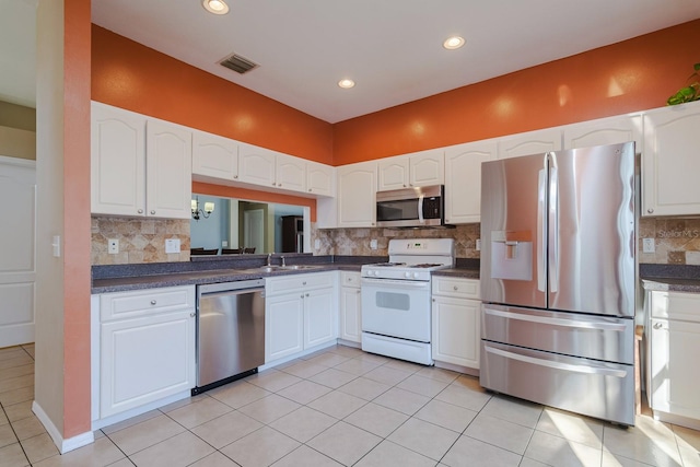 kitchen with decorative backsplash, stainless steel appliances, sink, light tile patterned floors, and white cabinets