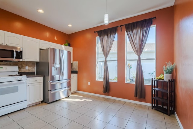 kitchen with backsplash, white cabinets, hanging light fixtures, light tile patterned floors, and stainless steel appliances