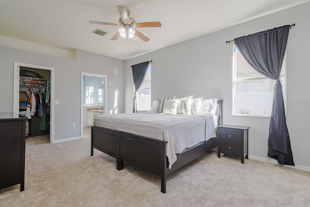 carpeted bedroom featuring ceiling fan, a spacious closet, ensuite bathroom, and multiple windows