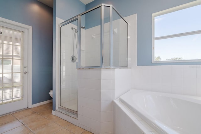 bathroom featuring tile patterned floors, toilet, a healthy amount of sunlight, and shower with separate bathtub