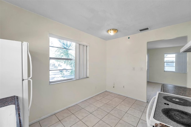 kitchen featuring light tile patterned floors, white refrigerator, and range