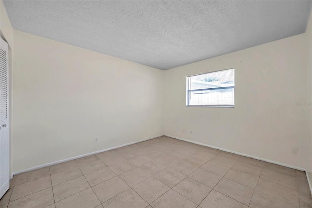 tiled spare room featuring a textured ceiling