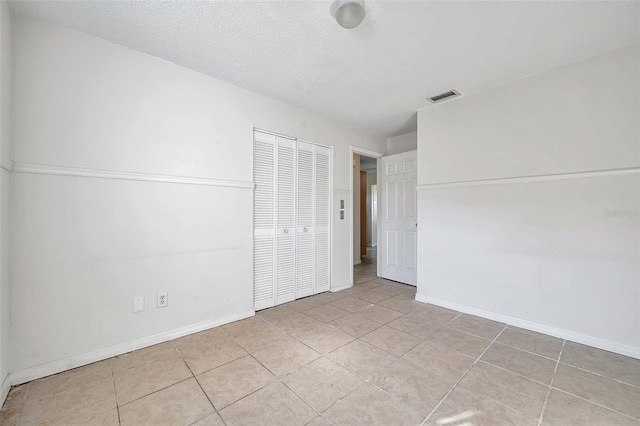 unfurnished bedroom featuring light tile patterned floors, a textured ceiling, and a closet