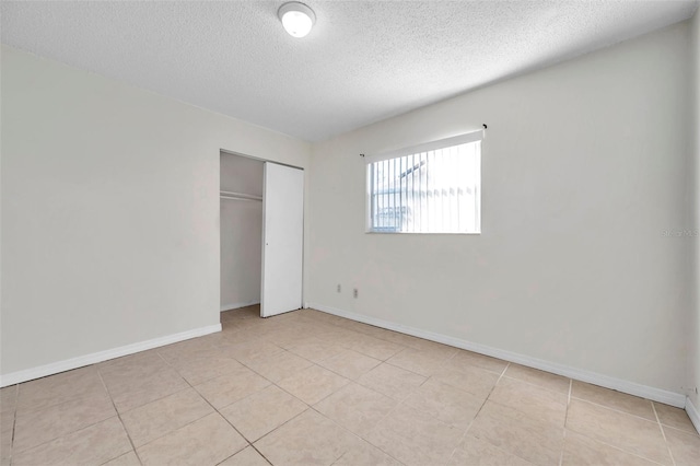 unfurnished bedroom featuring light tile patterned floors, a textured ceiling, and a closet