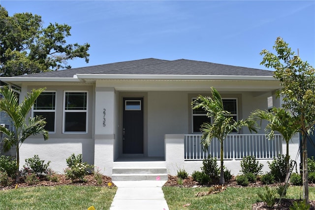 bungalow-style house with roof with shingles, stucco siding, and a porch