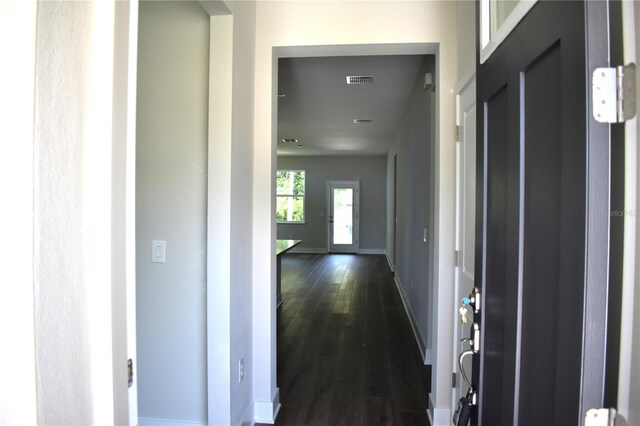 hallway with baseboards, dark wood-style floors, and visible vents