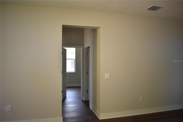 hallway with visible vents, dark wood-style flooring, and baseboards