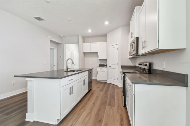 2735 36th Ave N, Saint Petersburg, FL 33713 - kitchen with appliances with stainless steel finishes, dark countertops, a sink, light wood-type flooring, and recessed lighting