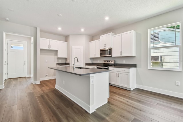 2735 36th Ave N, Saint Petersburg, FL 33713 - kitchen featuring stainless steel appliances, a sink, dark countertops, dark wood-style flooring, and baseboards