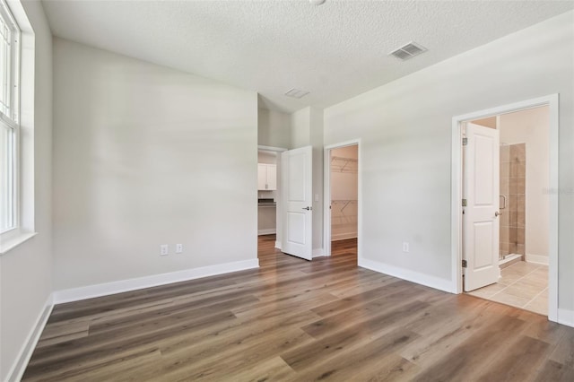 2735 36th Ave N, Saint Petersburg, FL 33713 - unfurnished bedroom featuring wood finished floors, a walk in closet, baseboards, a closet, and a textured ceiling
