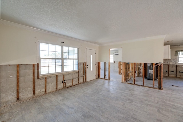 interior space with light wood-type flooring, a textured ceiling, and water heater