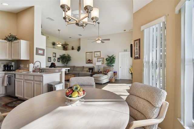 dining space featuring ceiling fan with notable chandelier, light wood-type flooring, sink, and a wealth of natural light