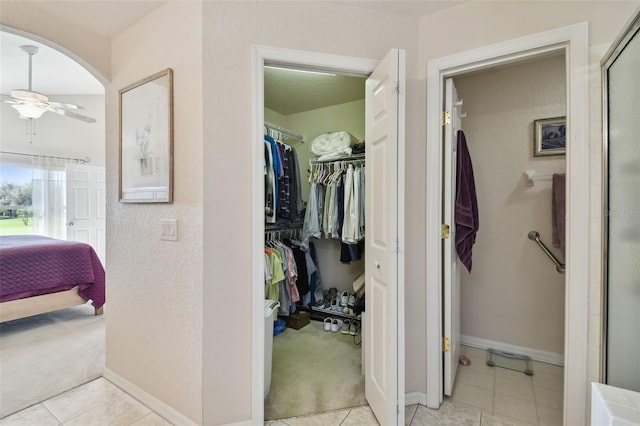 interior space with tile patterned flooring, ceiling fan, and a shower with shower door