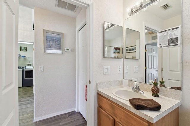 bathroom with wood-type flooring, vanity, an AC wall unit, and washer / dryer