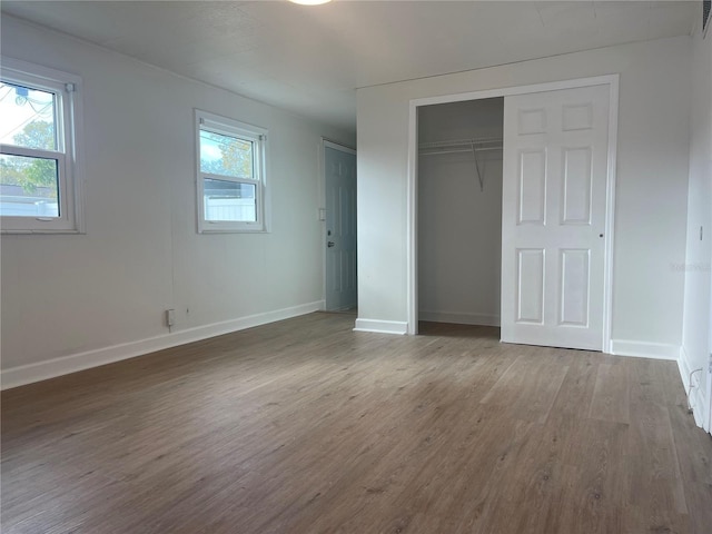 unfurnished bedroom with wood-type flooring and multiple windows