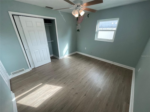 unfurnished bedroom featuring ceiling fan, a closet, and hardwood / wood-style flooring