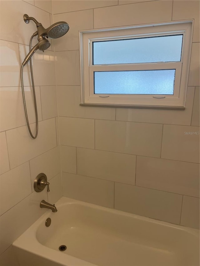 bathroom with tiled shower / bath combo and a healthy amount of sunlight